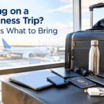 Business trip essentials including a suitcase, laptop, passport, smartphone, notebook, and professional clothing at an airport